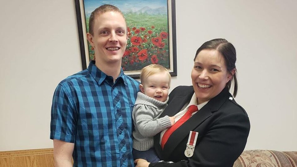 Portrait d'une femme en uniforme d'armée et d'un homme tenant un bambin. 