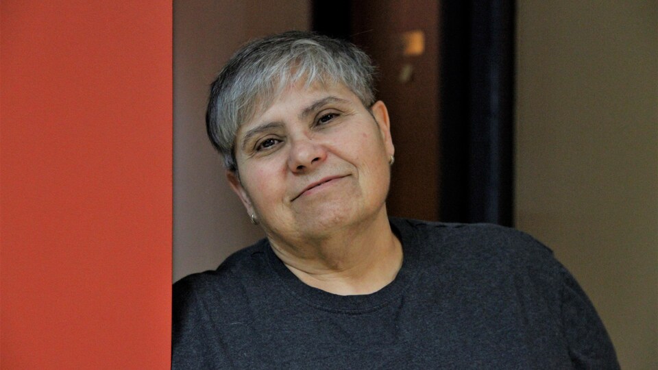 Diane Labelle adossée contre un mur rouge.
