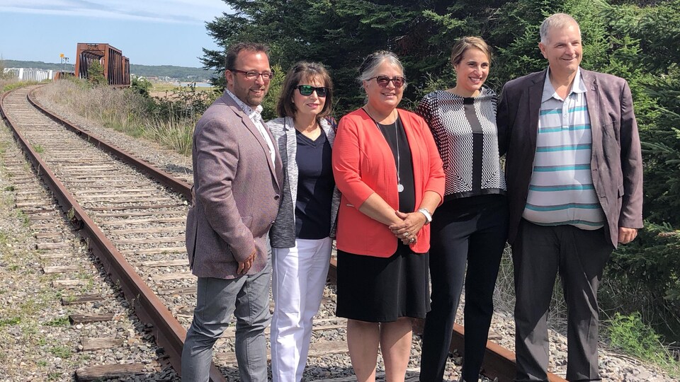 Les cinq élus se tiennent debout sur le chemin de fer et sourient pour la photo.