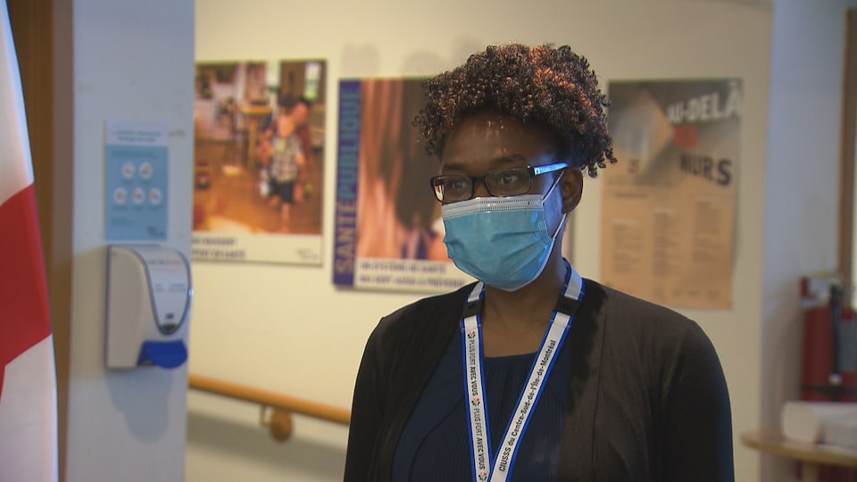 Une femme portant un masque se tient dans une clinique.