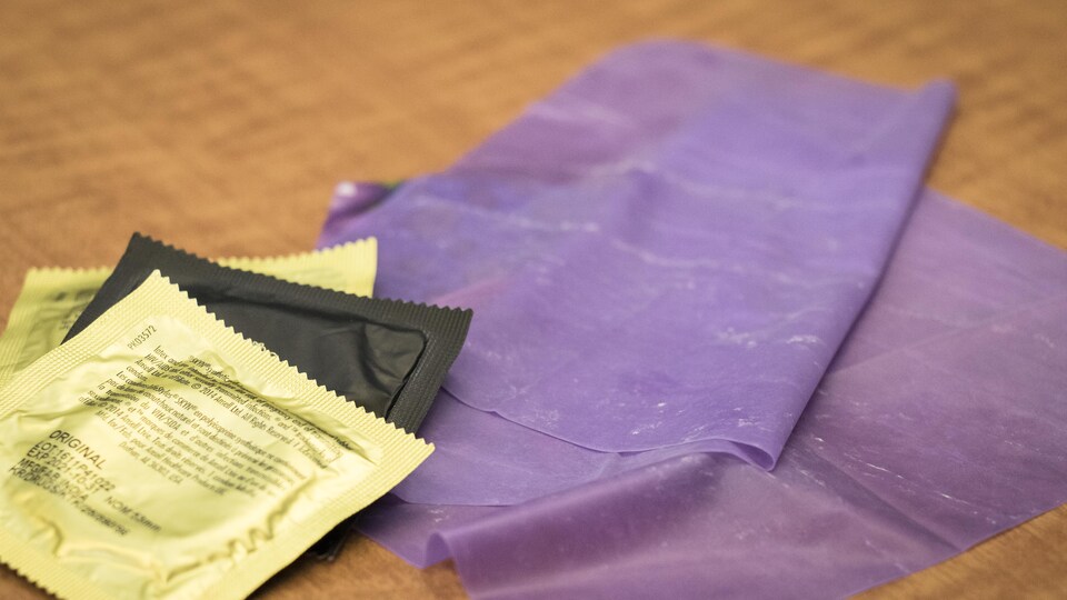 Condoms et digue dentaire mauve placés sur une table.