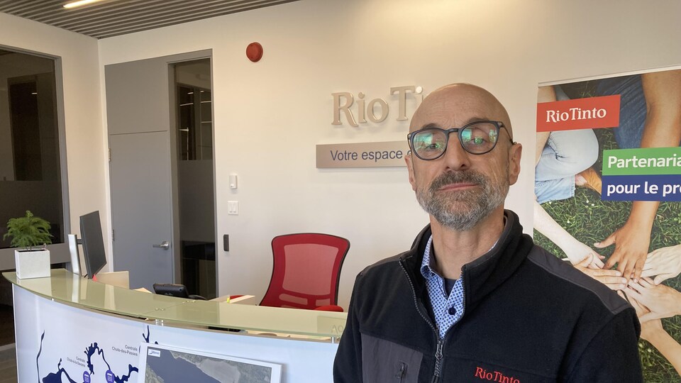 Simon Bergeron dans les bureaux de Rio Tinto à Arvida. Il se tient debout devant une carte indiquant les zones affectées en cas de bris de la digue entourant le lac de bauxite.