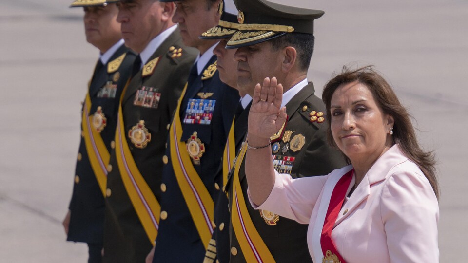 Dina Boluarte lève la main devant une rangée de soldats