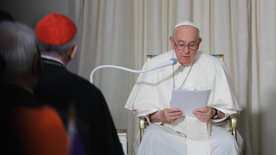 Le pape lit son discours dans un micro blanc.