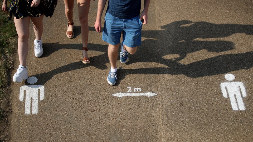 Des pictogrammes peints sur le ciment à Londres le 11 avril 2020 indiquent qu'il est recommandé de garder deux mètres de distance avec la personne la plus proche.