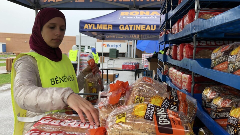 Une bénévole place des pains sur une étagère.