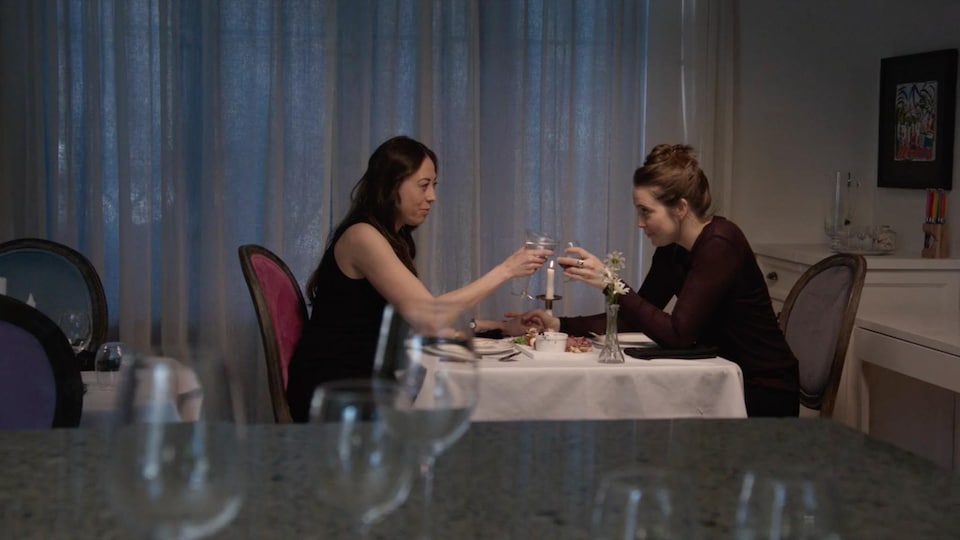 Les deux femmes sont assises à une table et trinquent.