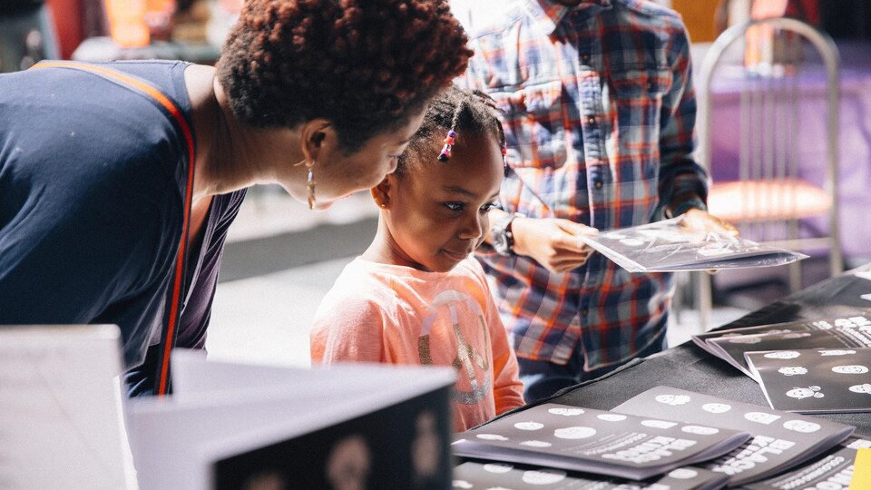 Une jeune fille regarde un livre à colorier.