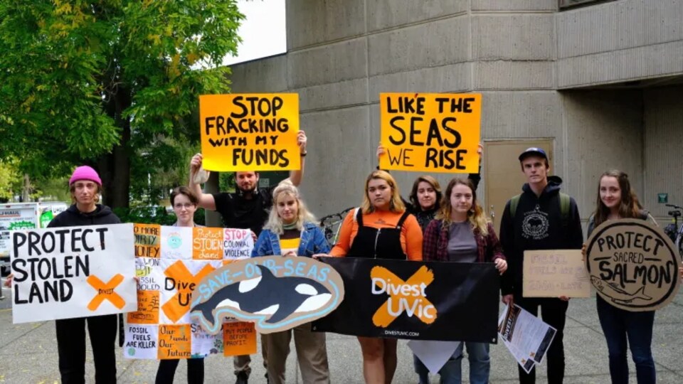 Un groupe de manifestants avec des pancartes qui demandent de désinvestir des énergies fossiles. 