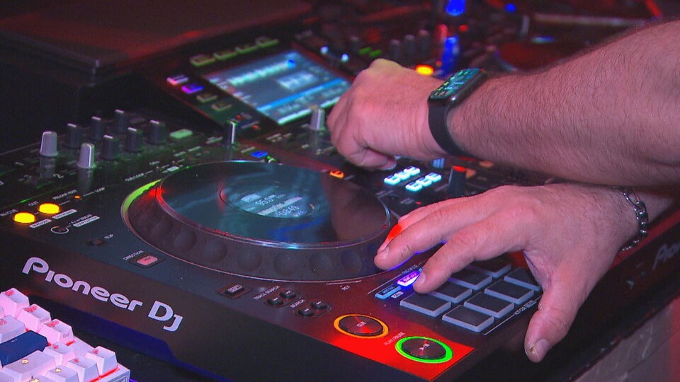 Des mains sur une console de DJ.