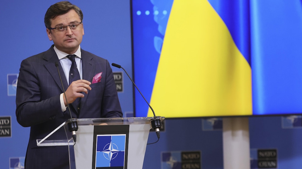 Dmytro Kouleba, devant un lutrin, près d'un écran affichant les couleurs du drapeau ukrainien