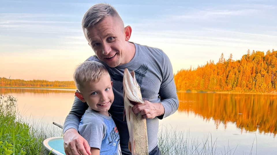 Ojciec trzymający rybę i syna nad jeziorem