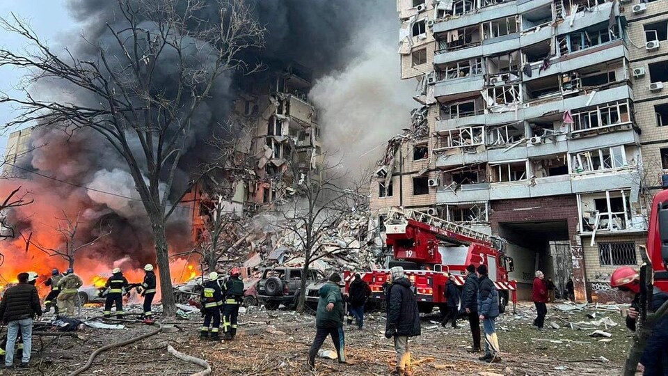 Des sauveteurs et des résidents s'activent près d'un immeuble d'habitation frappé par un tir de missile russe à Dnipro.