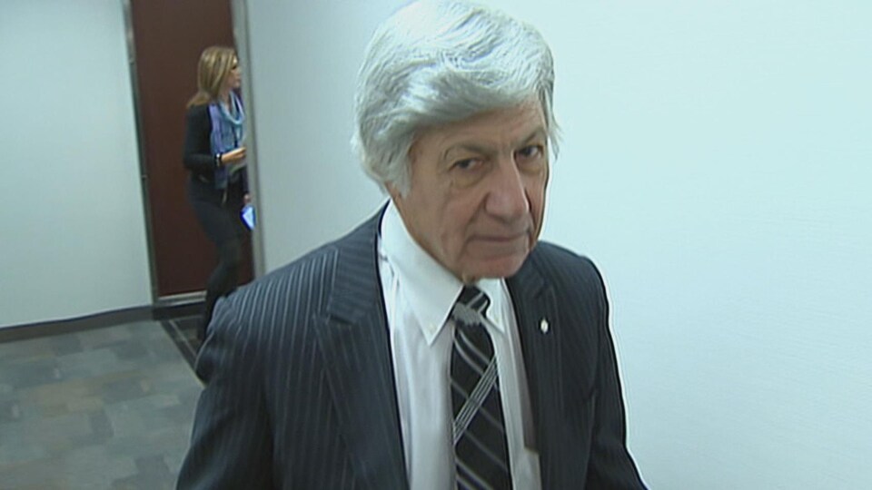 Bernard Norman Barwin marche dans un corridor.