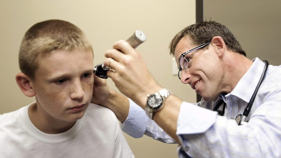 Photo d'un docteur qui examine les oreilles d'un enfant.