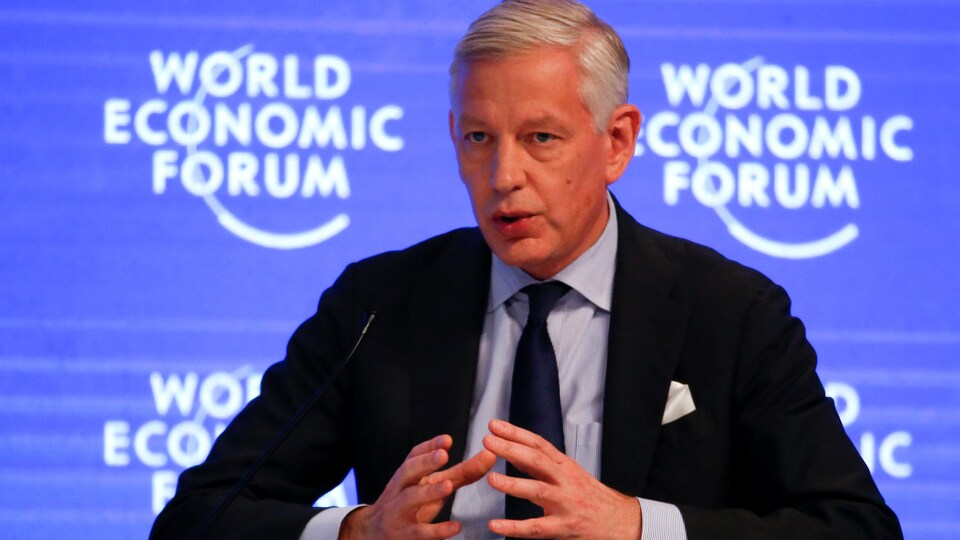 Dominic Barton, assis, parle devant un micro.