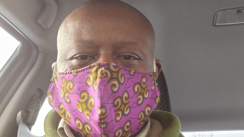Un homme noir avec un masque dans une voiture.