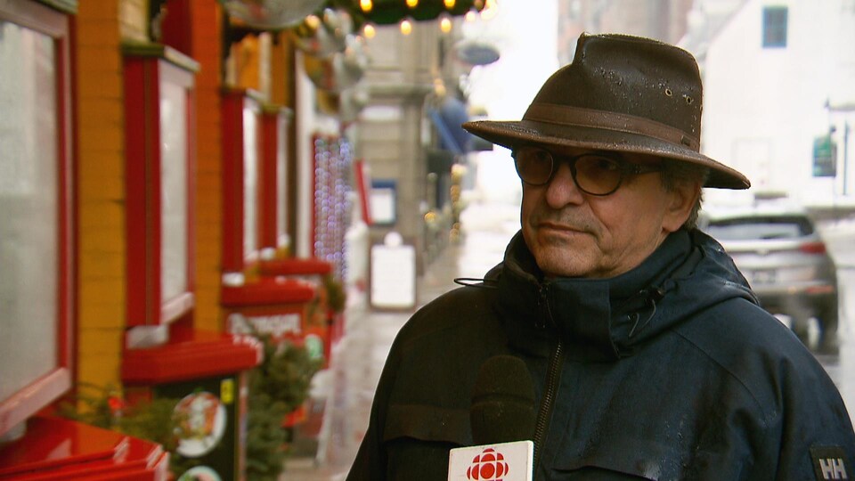 Donald Gilbert accorde une entrevue à Radio-Canada à l’extérieur, en hiver, en bordure de la rue Saint-Louis.
