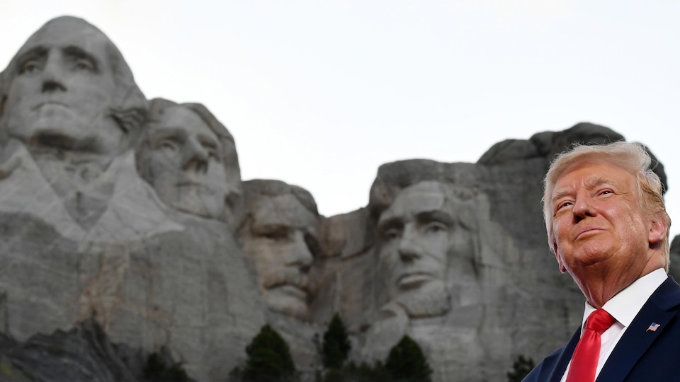 Donald Trump au mont Rushmore. En arrière-plan, les anciens présidents George Washington, Thomas Jefferson, Theodore Roosevelt et Abraham Lincoln, dont les visages sont sculptés dans le granit.