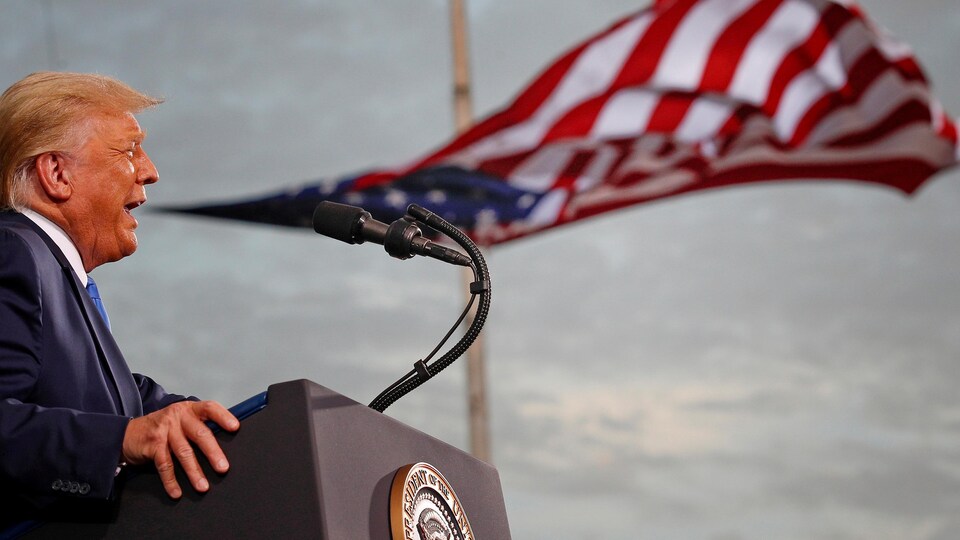 Donald Trump devant un drapeau américain.
