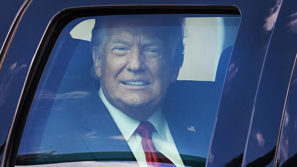 Gros plan de Donald Trump à l'intérieur d'une voiture.