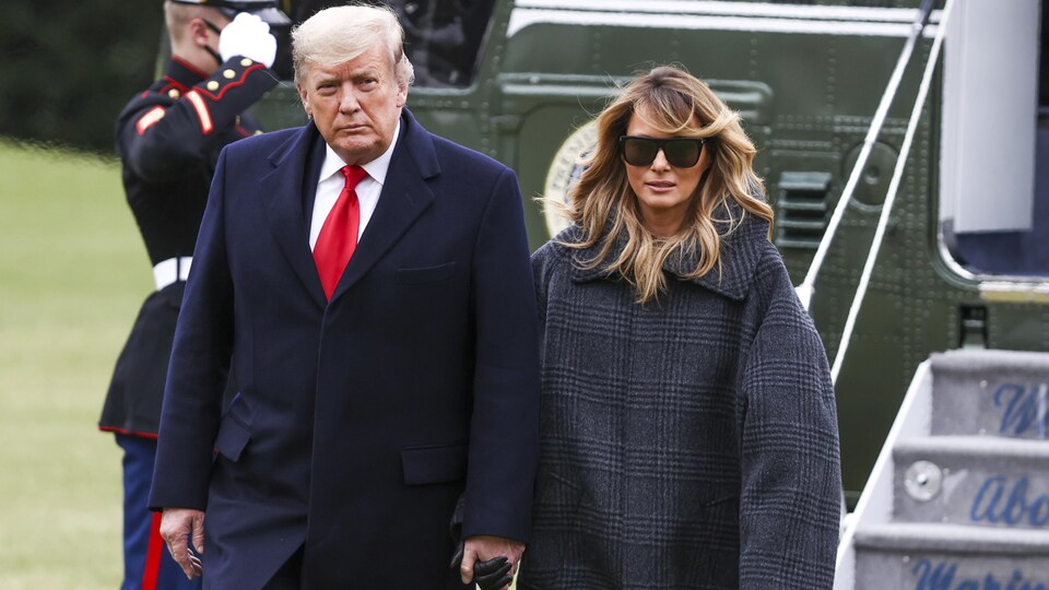 Donald Trump tenant la main de son épouse Melania devant l'avion.