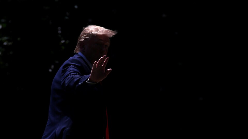 On ne distingue que la chevelure et la main de M. Trump sur cette photo prise dans la pénombre.