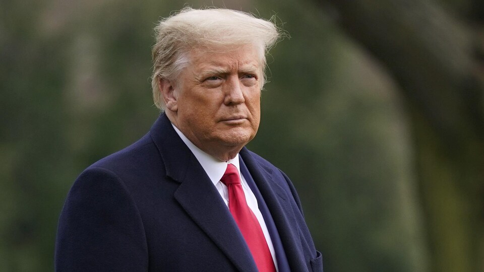 Donald Trump photographié dehors devant des arbres.
