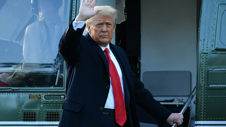 Donald Trump fait un salut de la main près d'un hélicoptère. 