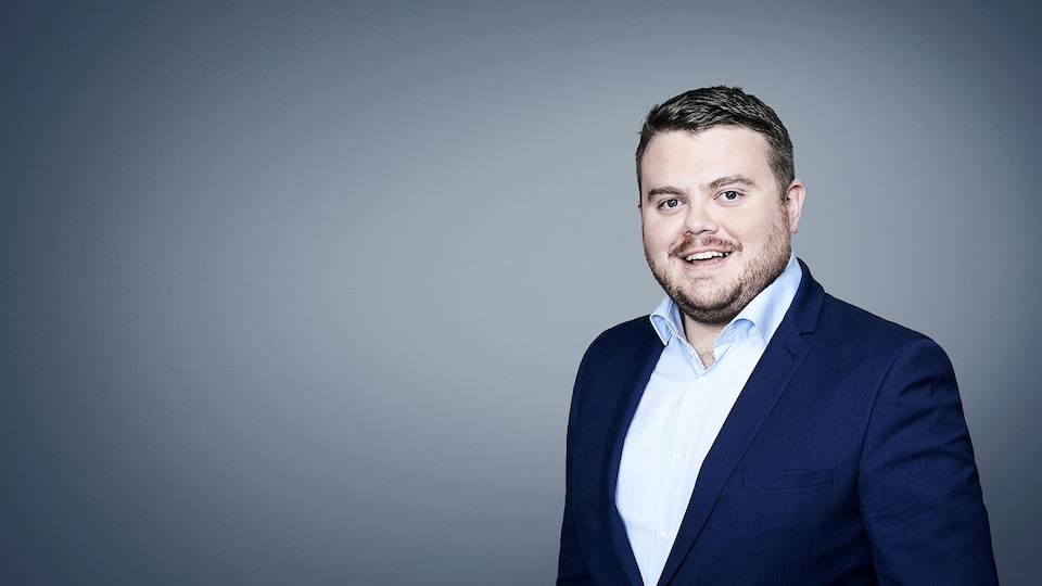 Portrait d'un jeune journaliste en veston et chemise.