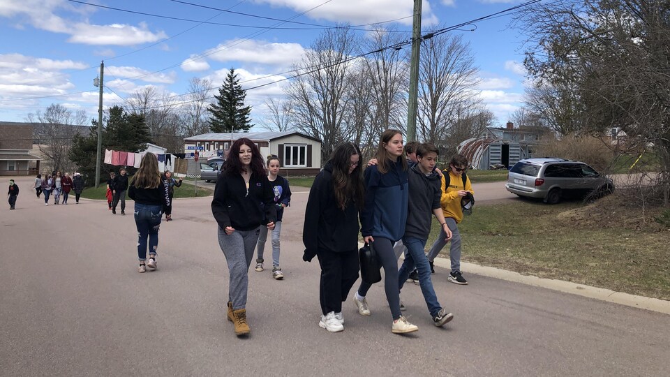 Young people walk down the street, looking sad. 