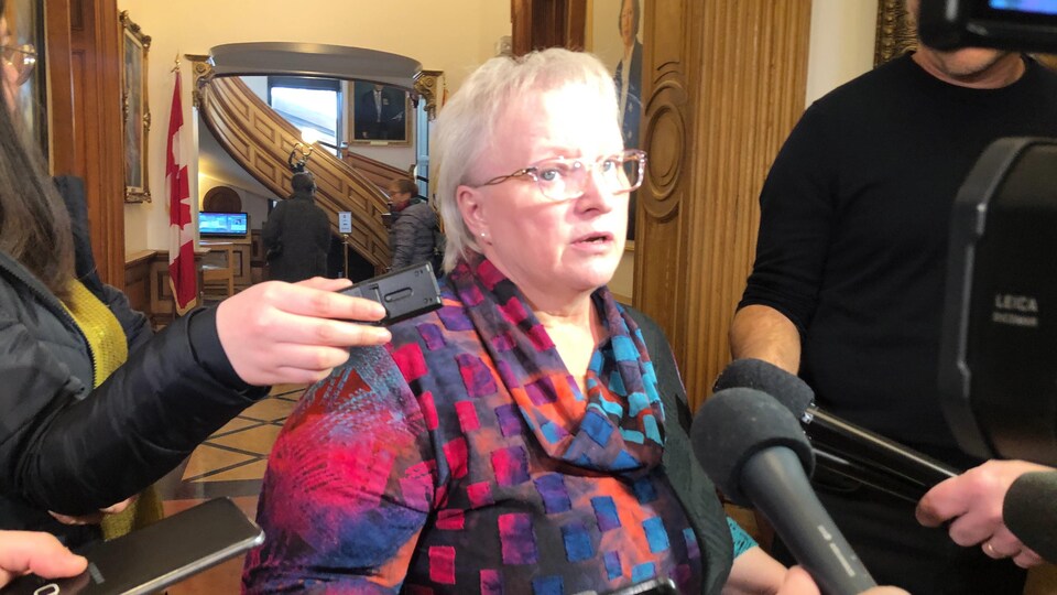 Dorothy Shephard entourée de micros durant une mêlée de presse dans un corridor de l'édifice de l'Assemblée législative.