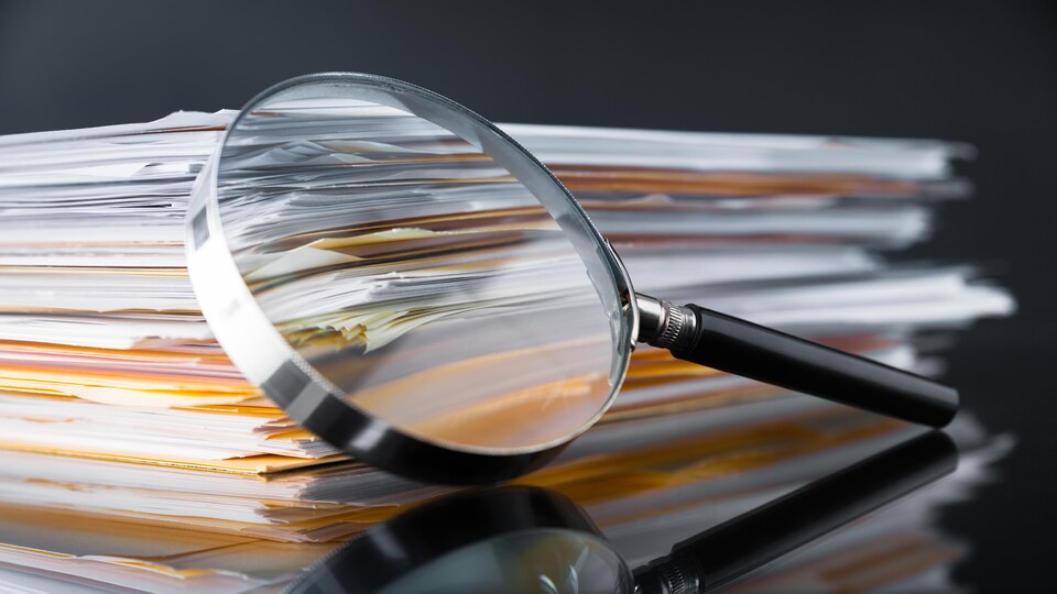 Une loupe est posée sur des documents.