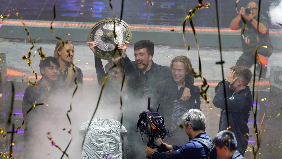 Les joueurs qui ont remporté le tounoi de Dota 2 the International célèbrent leur victoire en tenant un trophée.
