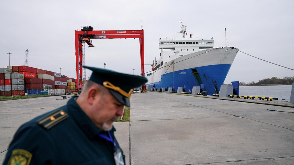 Un homme en uniforme, près d'un navire amarré.