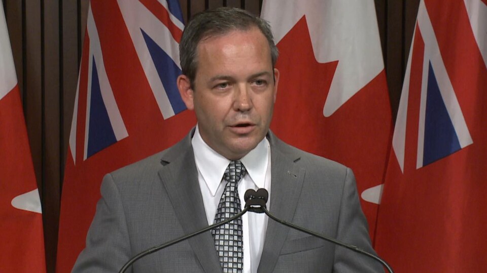 A man at a press conference in front of flags