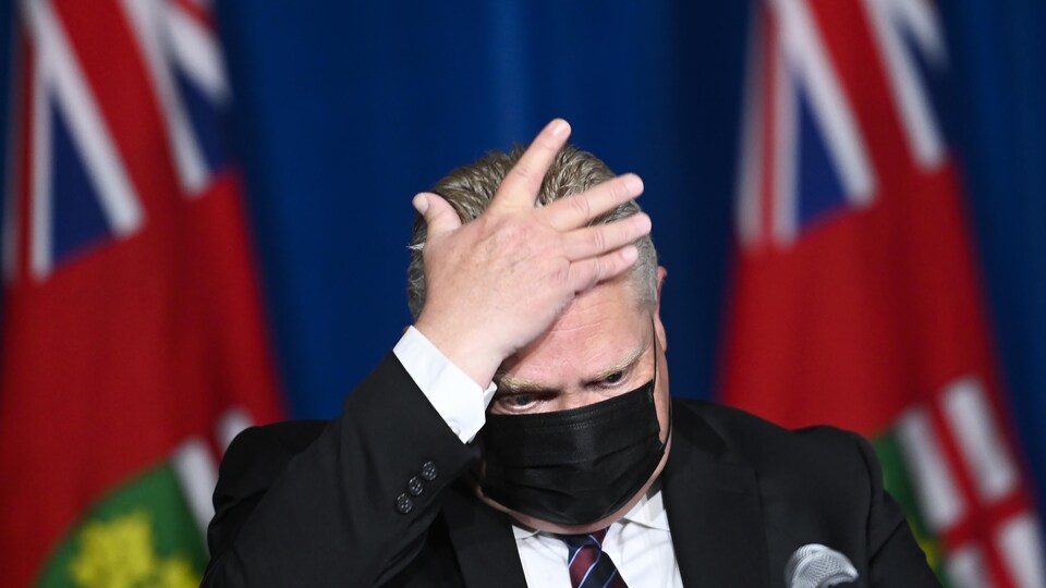 Le premier ministre de l'Ontario, Doug Ford, se touche le front lors d'une conférence de presse.