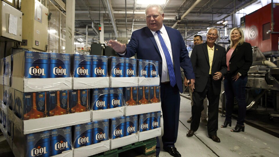 Un homme à côté d'une pile de caisses de bière