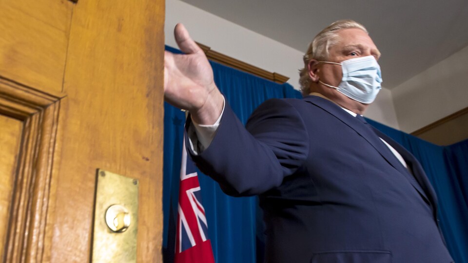Doug Ford, masqué, refermant une porte.