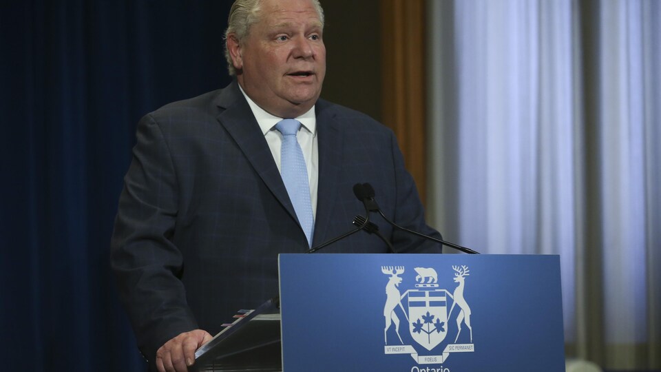 Un homme en complet debout devant un podium.