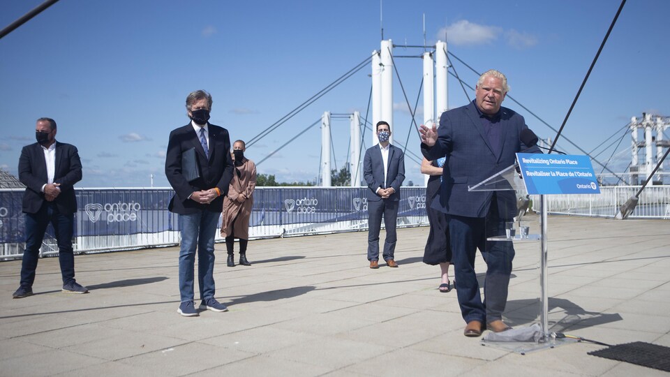 Doug Ford a dévoilé les plans de revitalisation de la Place Ontario lors d'un point de presse le 30 juin. Il parle devant un lutrin, flanqué par le maire de Toronto.