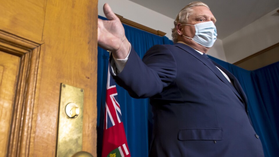 Doug Ford porte le masque et s'apprête à fermer une porte.