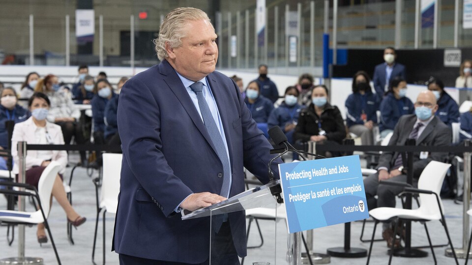 Le premier ministre Doug Ford écoute une question lors d'une conférence de presse à un aréna transformé en centre de vaccination à Toronto.