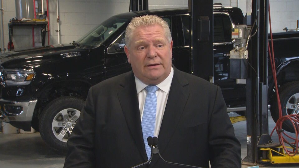 Doug Ford en point de presse dans un garage devant une camionnette.