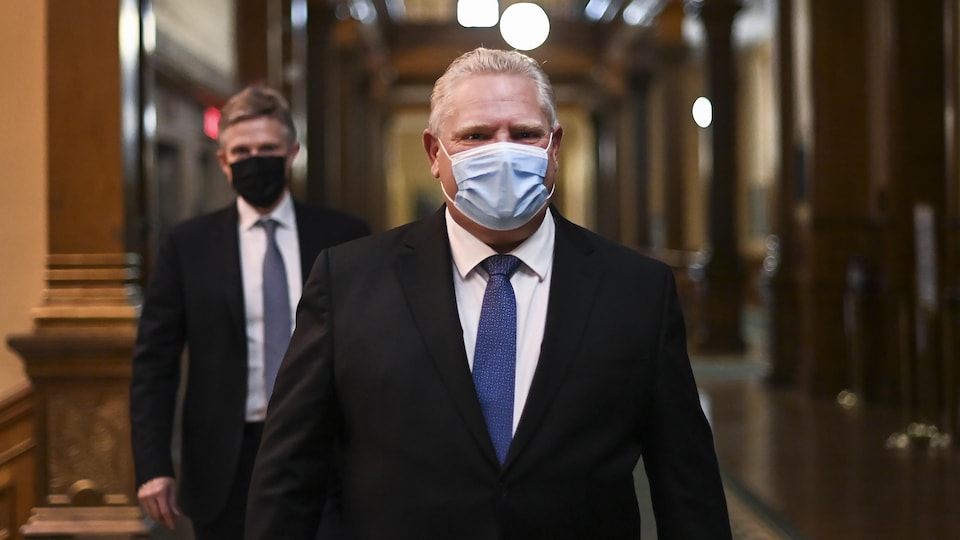 Doug Ford en compagnie de son ministre des Finances, Rod Phillips, marchent dans un corridor à Queen's Park.