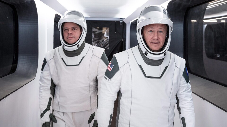 Les deux hommes marchent vêtus de leur combinaison d'astronaute.