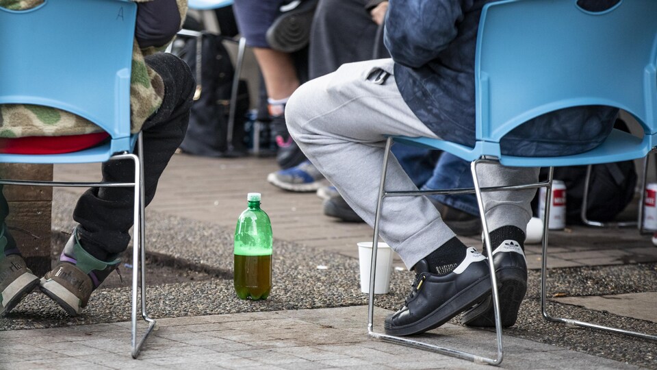 Des personnes assises sur des chaises disposées en cercle avec des bouteilles et des cannettes d'alcool à terre à leurs pieds.