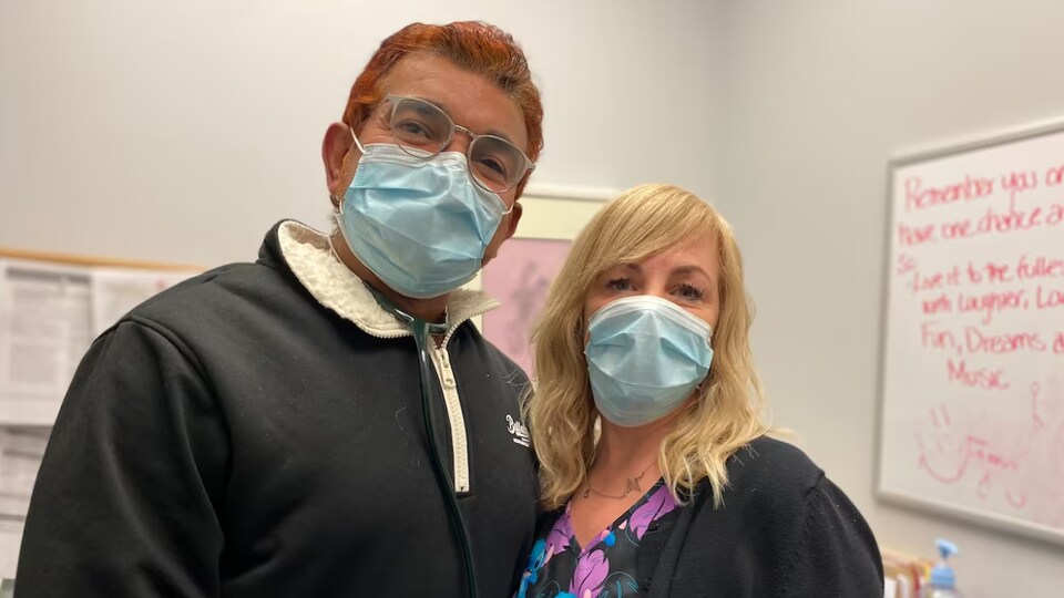 Un médecin et une collègue posent avec un masque.