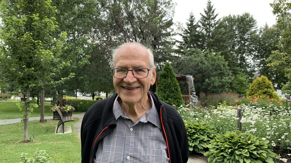 Le Dr Pierre Vincelette sourit à la caméra. Il se trouve dans un parc à Rouyn-Noranda.