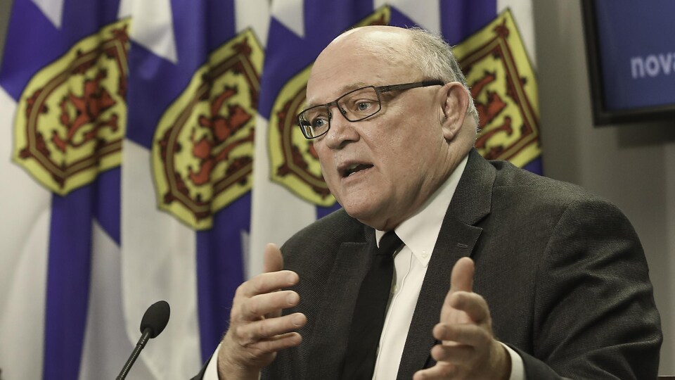 Robert Strang gesticule en expliquant quelque chose en conférence de presse.